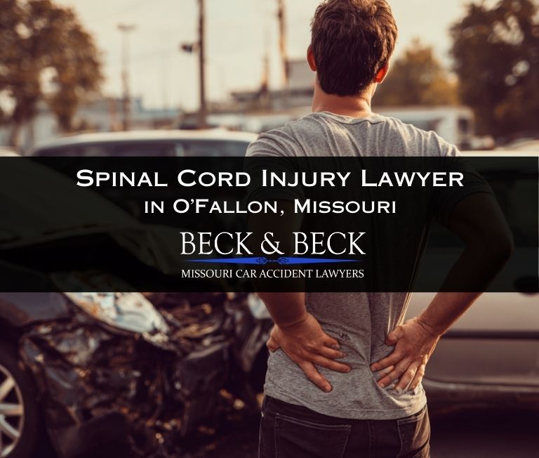 Young man standing next to a crashed car holding his back showing visible pain at an intersection in O'fallon, Missouri