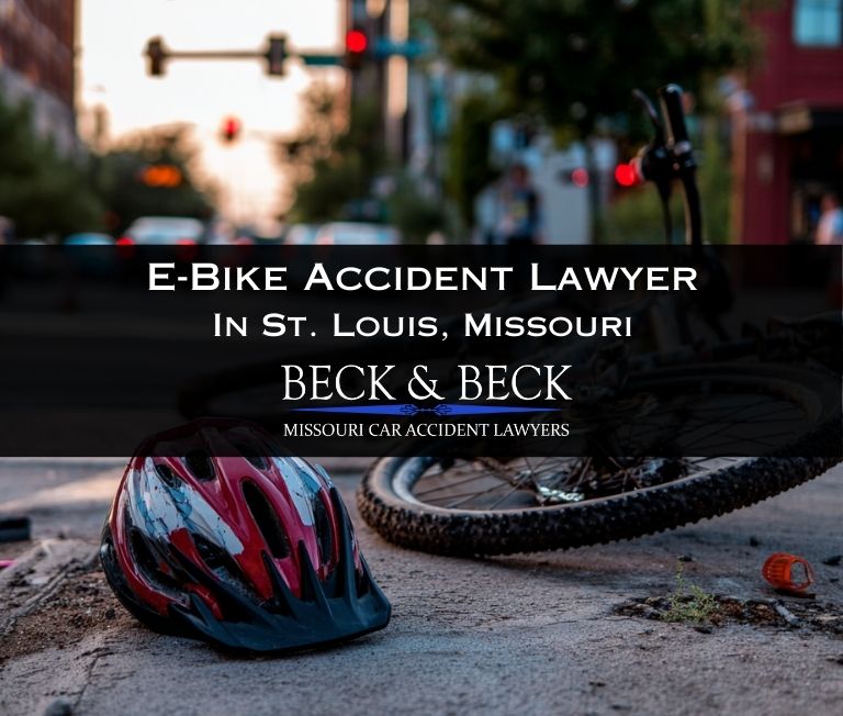 Crashed e-bike on its side with a bicycle rider's helmet next to it on a street in St. Louis Missouri