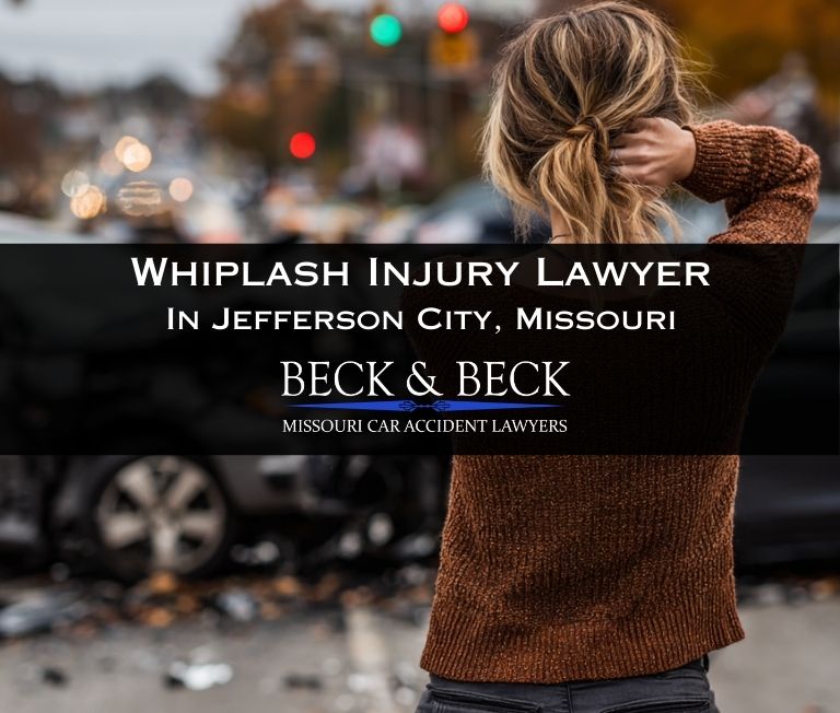 Two cars after a serious crash in an intersection in Jefferson City, Missouri with woman standing next to her car showing extreme neck pain