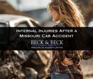 Woman standing next to her crashed car in Missouri with her hands on her back in pain