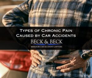 Man with chronic pain standing next to his car with his hands on his lower back after an accident in St. Louis, Missouri