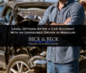 Man standing next to his crashed car with his arms crossed after an accident caused by an uninsured driver in St. Louis, Missouri